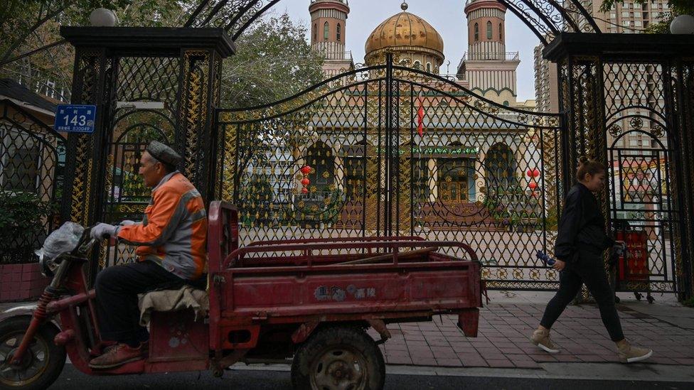 This photo taken on September 11, 2019 shows people walking past a mosque in Urumqi, the regional capital of Xinjiang.