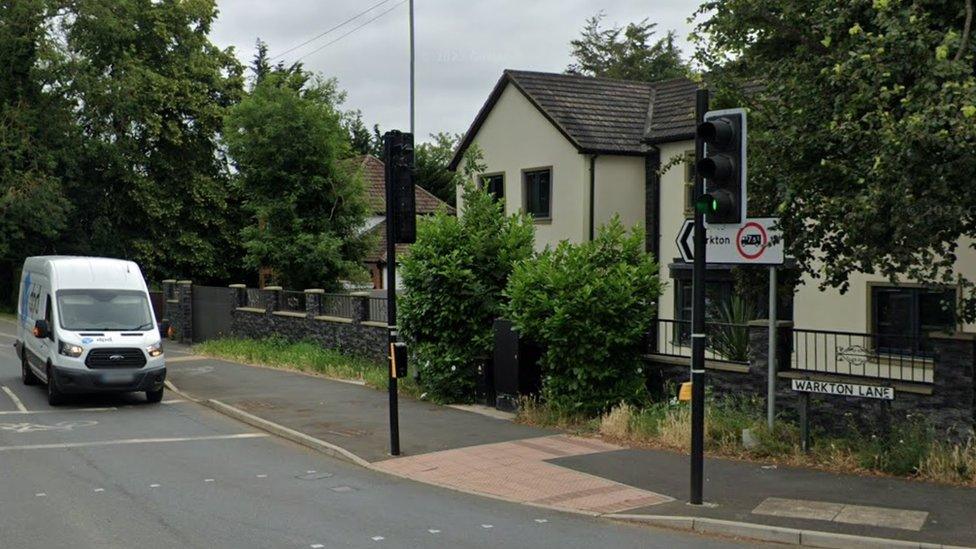 Village road junction with "Warkton Lane" sign