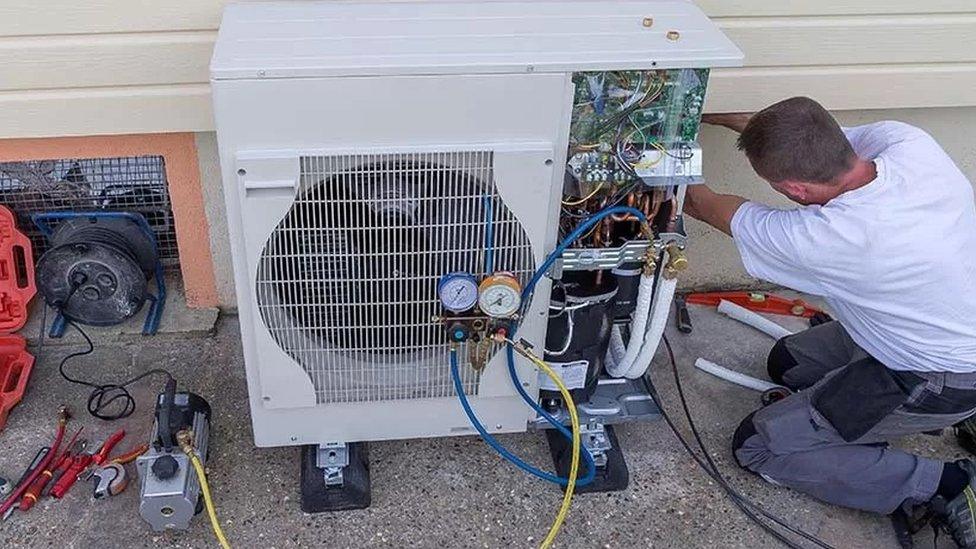 A man working on a heat pump