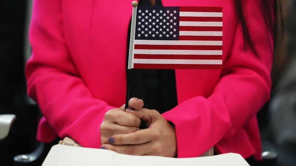 Woman holds flag during naturalisation ceremony