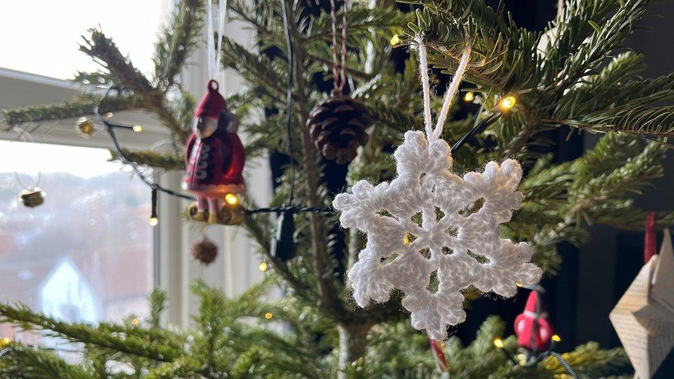 a crocheted snowflake garland hanging on a christmas tree with other baubles