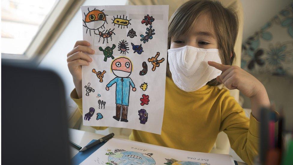 A little boy in a mask with drawings of a virus