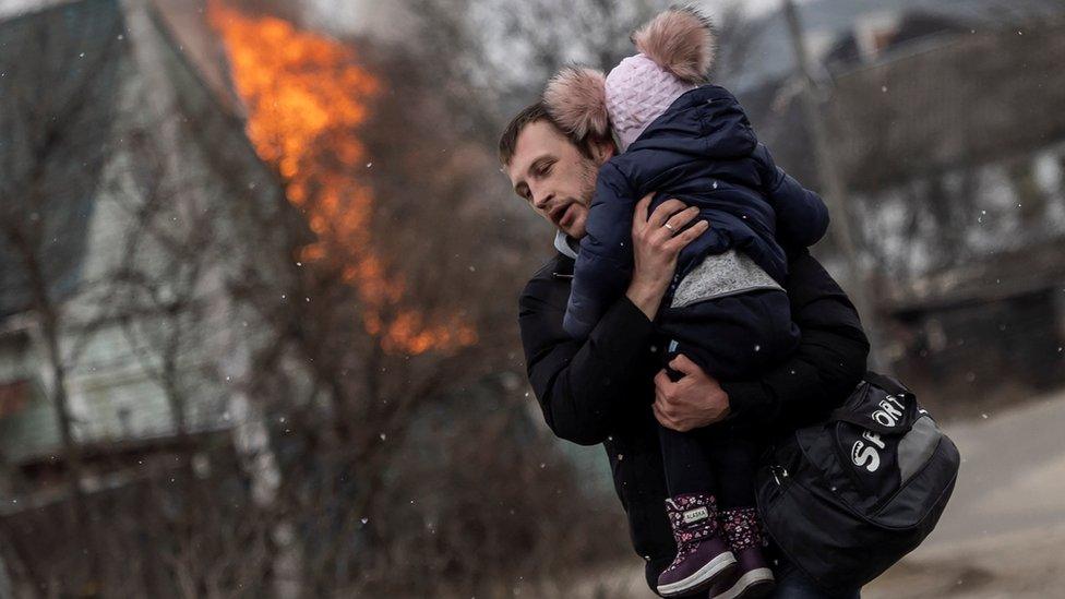 A man and a child escape from the town of Irpin after heavy shelling on the only escape route used by locals