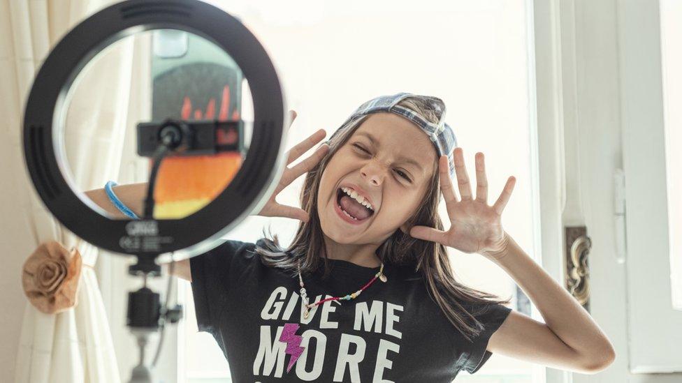 Happy young blogger using smartphone and Ring Light at home