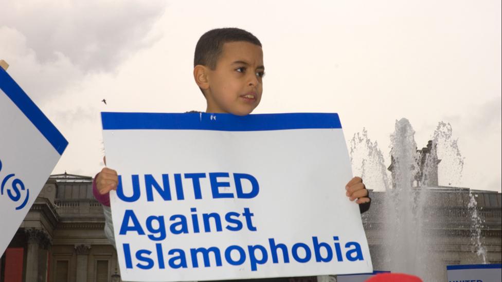 A boy holds up a placard reading "United against Islamophobia"