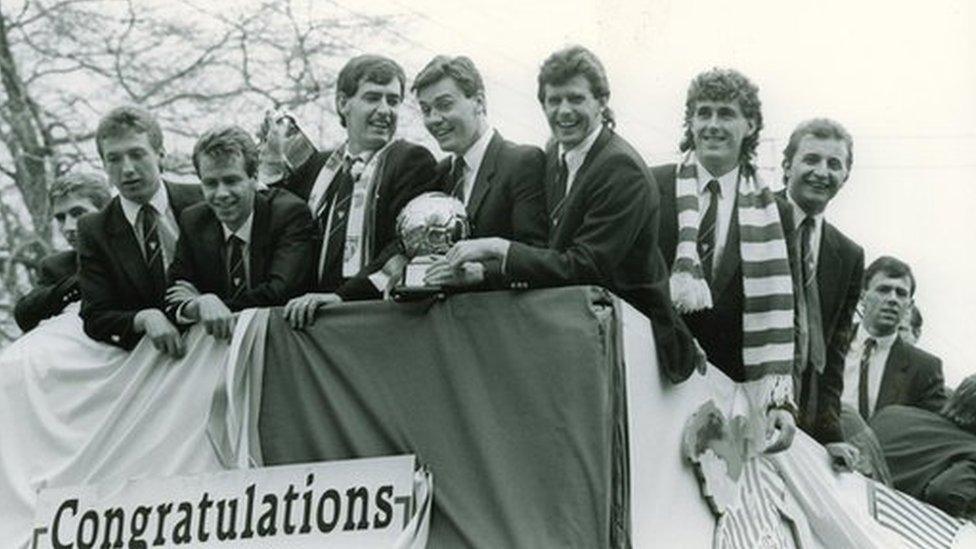 Members of the triple winning team celebrate on an open top bus