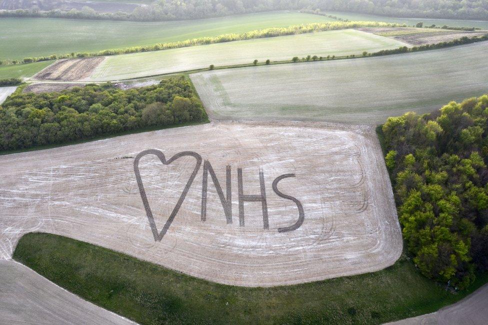 An aerial view on to a field in which NHS and a heart sign has been marked out using crops