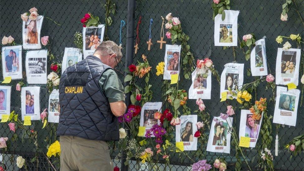 A man prays in front of a missing persons wall near a collapsed apartment block in Miami, Florida, June 2021