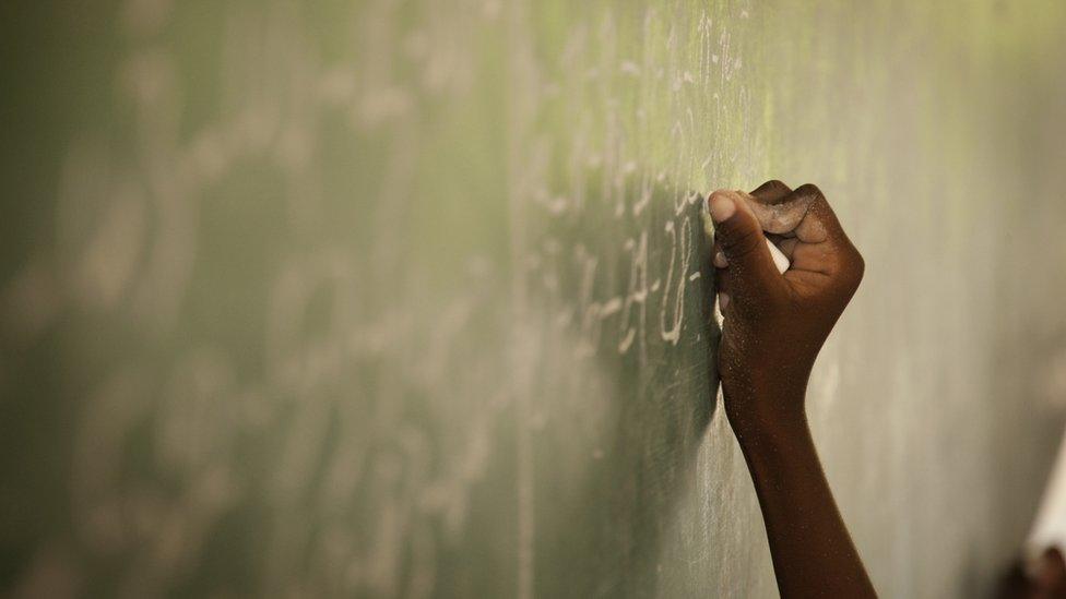 A student writes on a blackboard