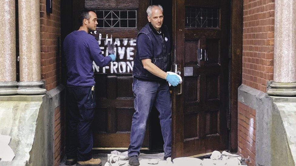 Photo of cleaners removing graffiti from a door