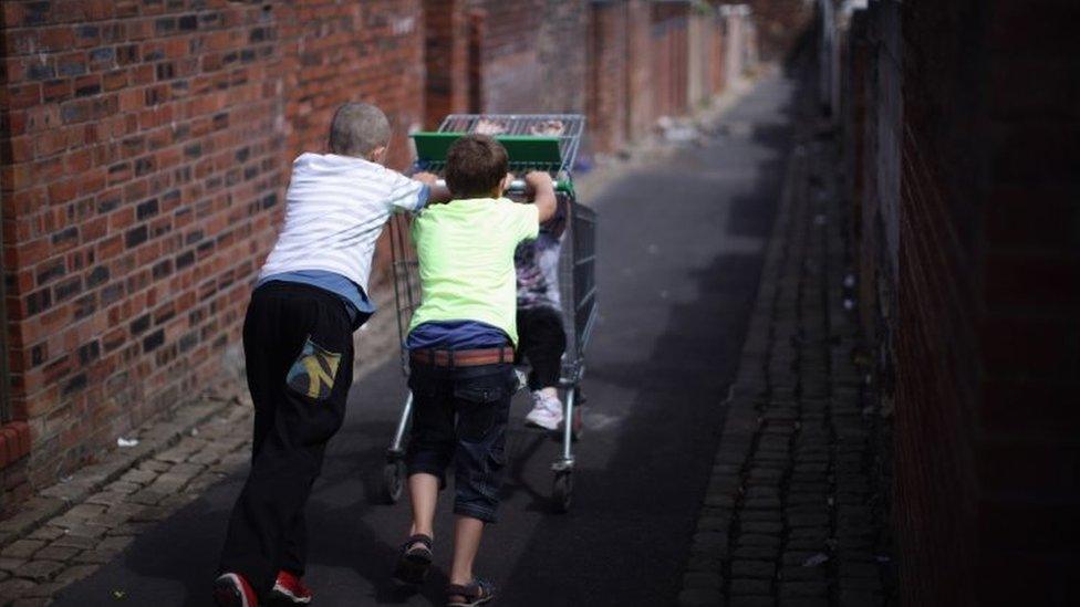 Children play with a discarded shopping trolley in the back alleys