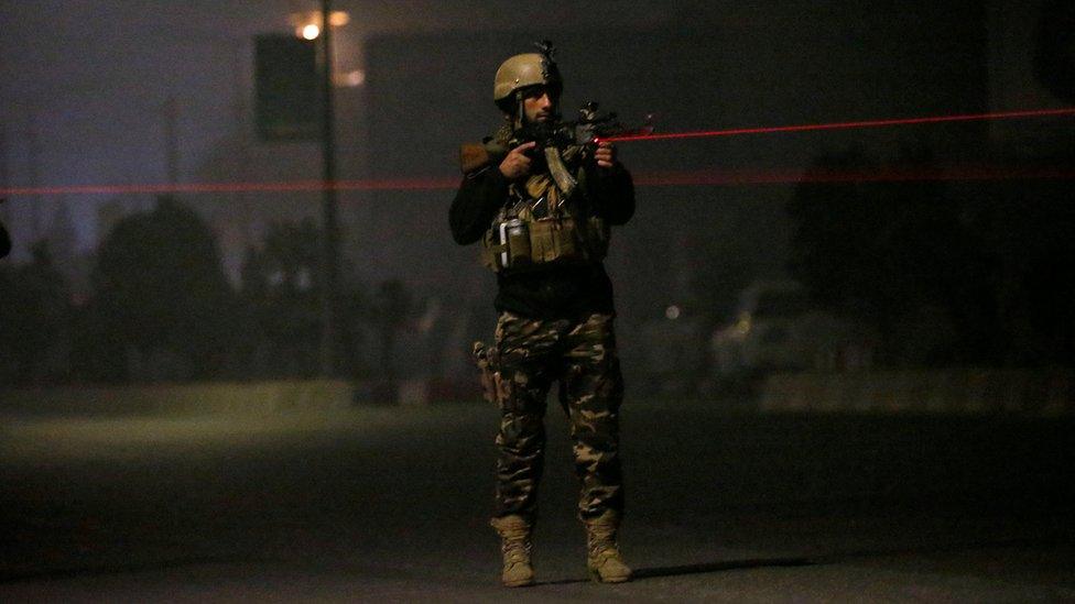 Afghan security officer trains a laser sight on a target off-camera