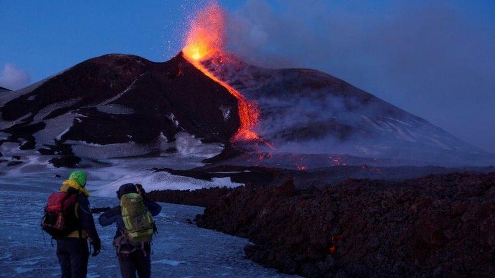 Volcano guides stand in front of Italy"s Mount Etna, Europe"s tallest and most active volcano