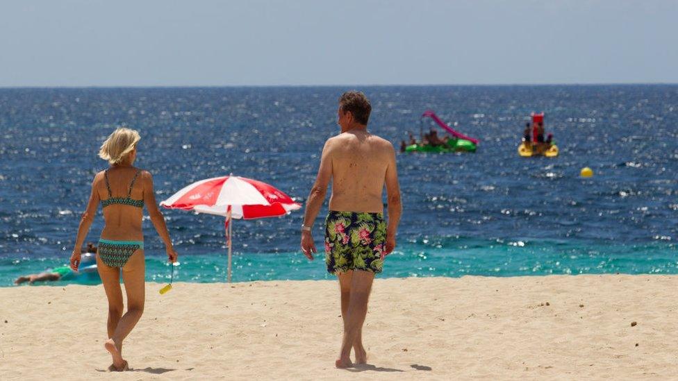 Tourists walk at Magaluf Beach in Calvia, on the Balearic Island of Mallorca.