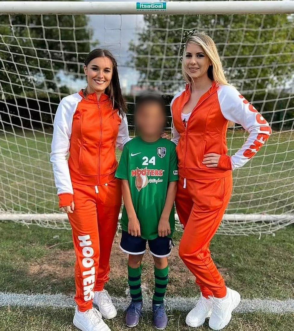 A young football player with two women from Hooters