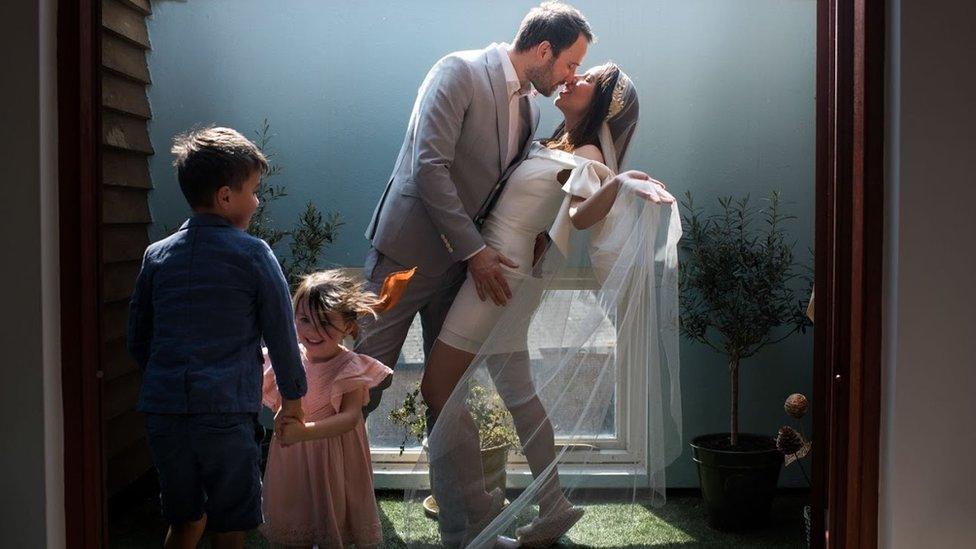 Couple in wedding outfits and children in back garden