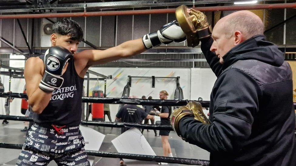 Ahsan Karimi in training with John Conway on the right holding the pad