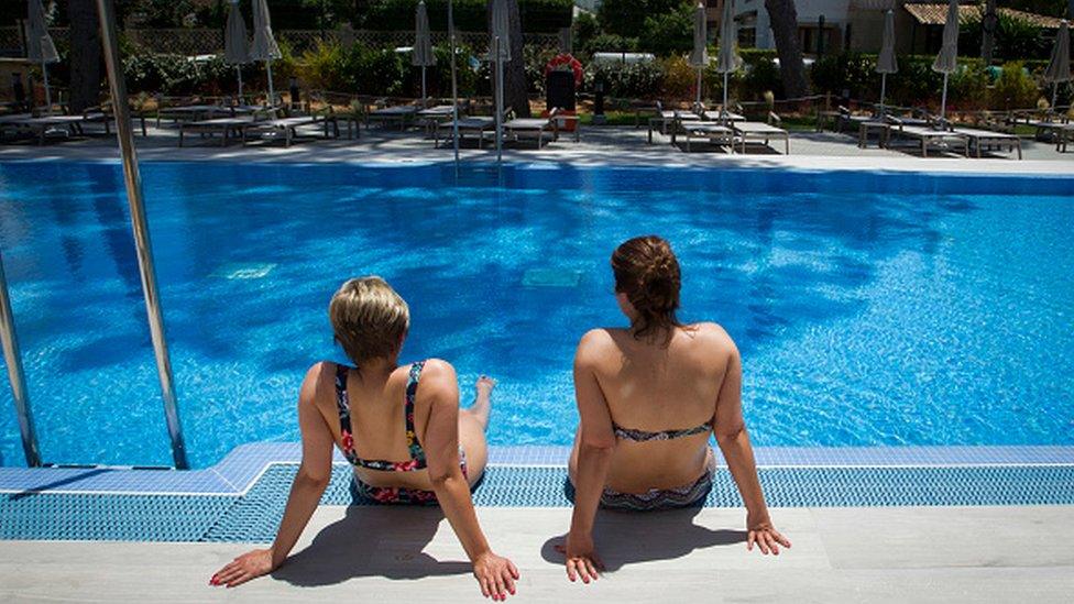 German tourists sit at a swimming pool in Majorca