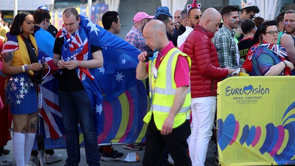 worker walks past venue queus