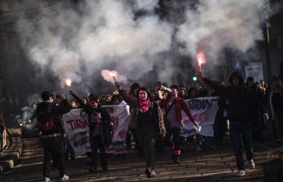 Women light flares during a protest rally in Milan, Italy