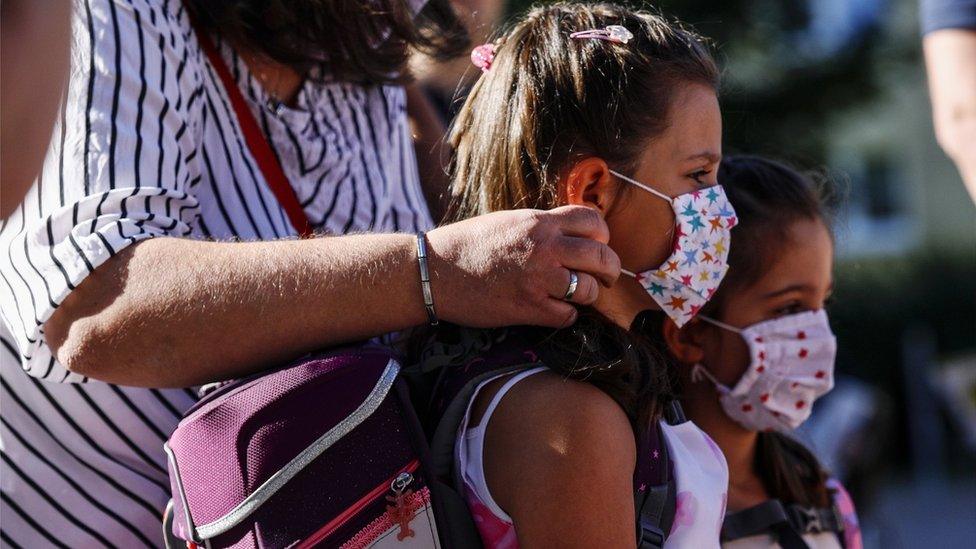 Children have their masks adjusted on the way to school in Germany