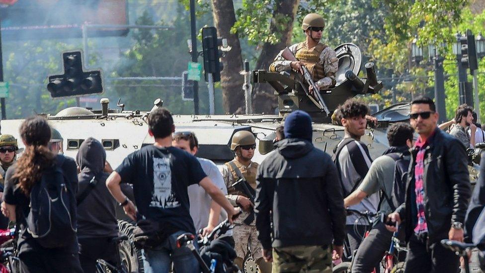 A soldier in a tank is surrounded by demonstrators in Santiago