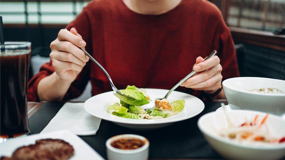 Stock image of a woman eating a variety of dishes