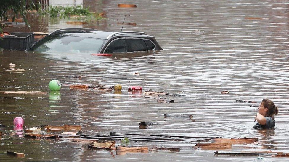 A woman is trying to move in a flooded street following heavy rains in Liege