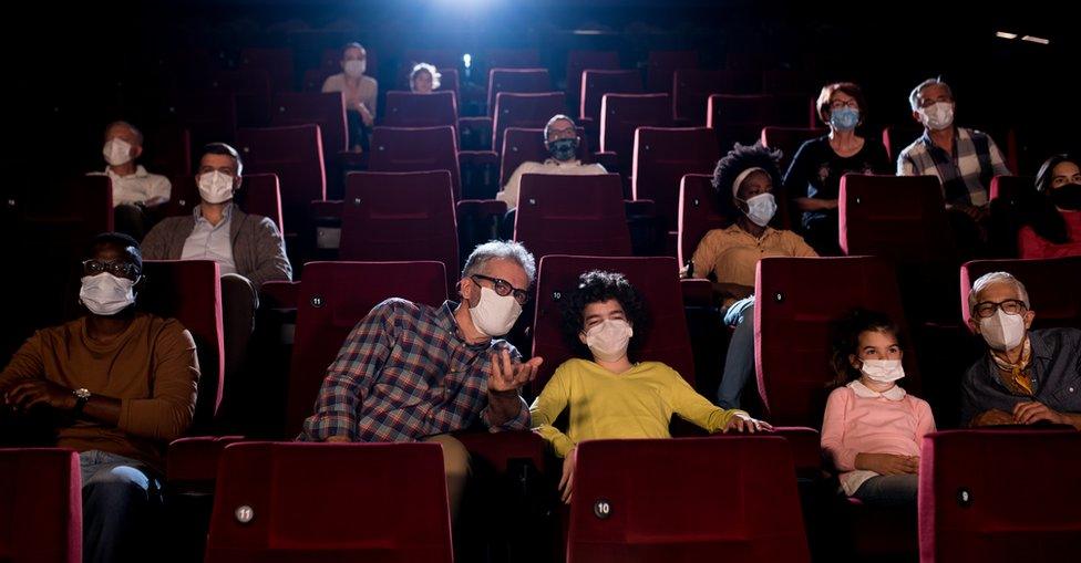 Stock image of people watching a performance while wearing facemasks