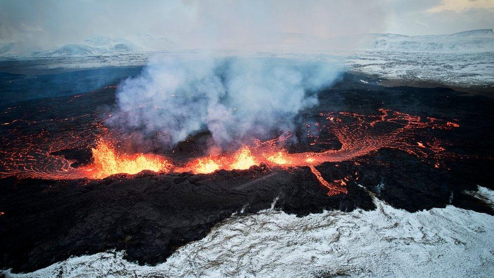 An aerial view taken with a drone shows lava and smoke spewing from a volcanic fissure during an eruption, near the town of Grindavik, in the Reykjanes peninsula, southwestern Iceland, 19 December 2023.