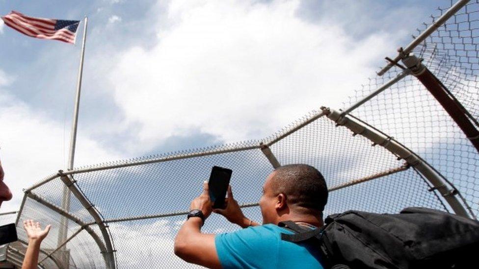 A Cuban migrant takes a photo in front a US flag after arriving by plane from Panama to Mexico (May 2016)