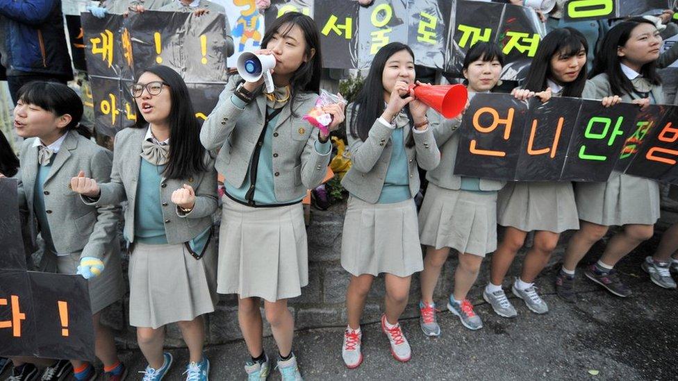 Secondary school students cheering on classmates during exam season in South Korea