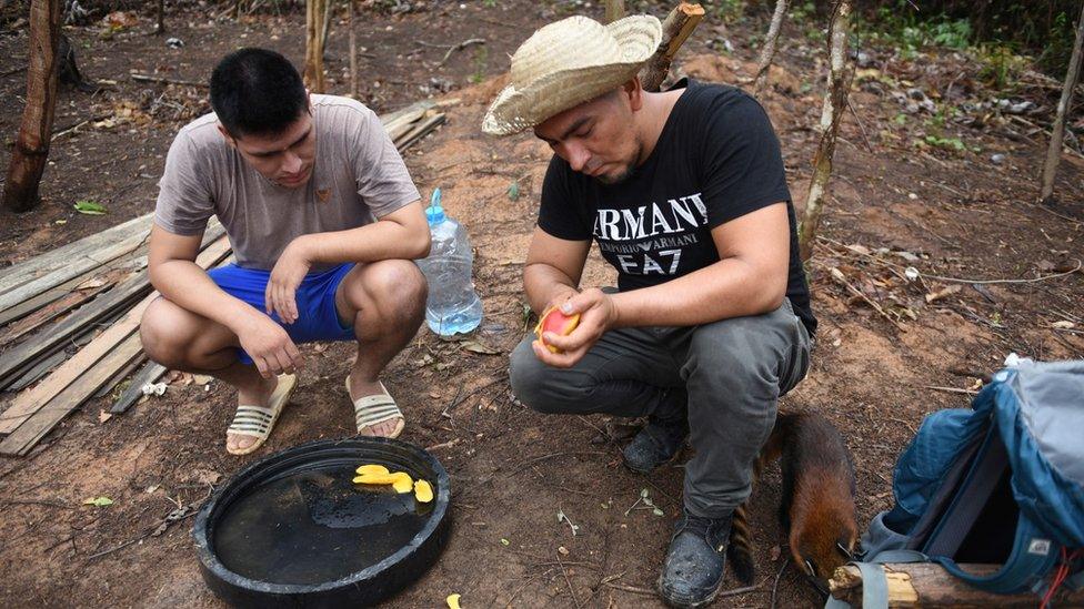 Two local men prepare water and fruit to leave for animals affected by the fires