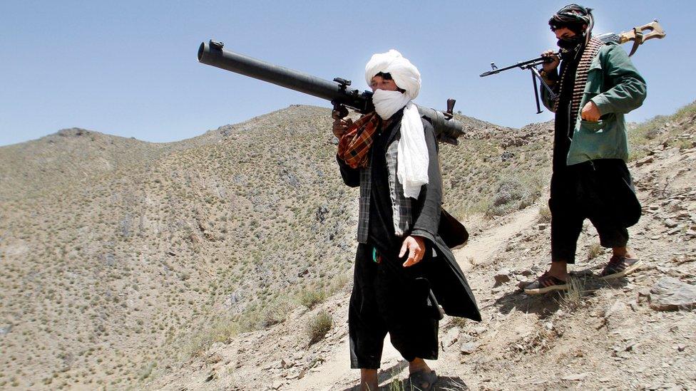 Members of a breakaway faction of the Taliban fighters walk during a gathering , in Shindand district of Herat province, Afghanistan