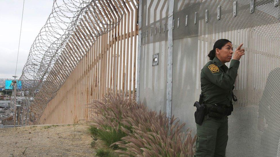 A US Border Patrol agent talks across a fence in San Diego, California.