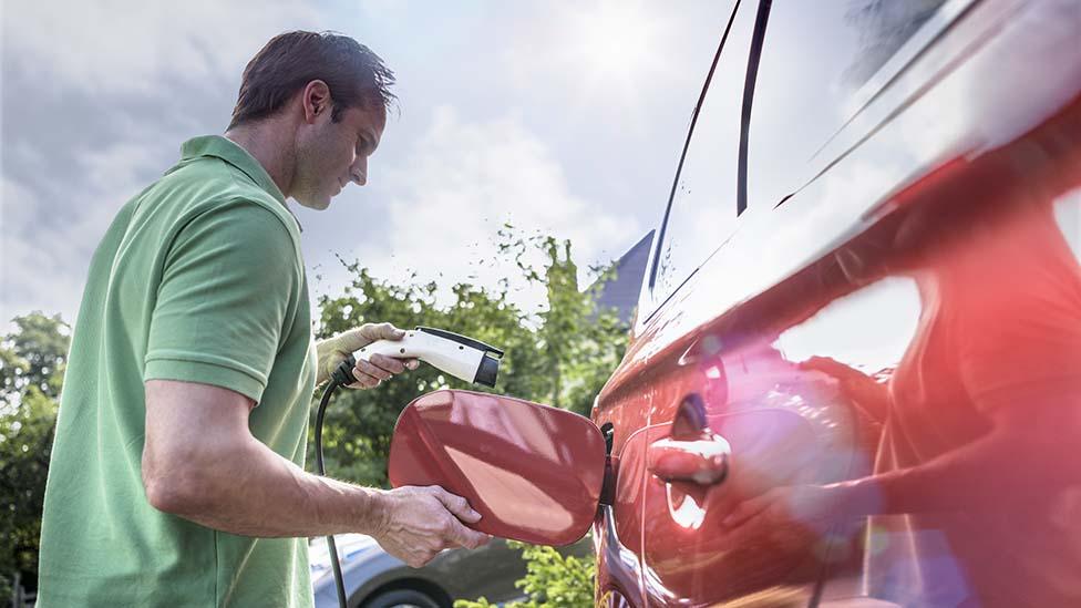 Man charges red electric car