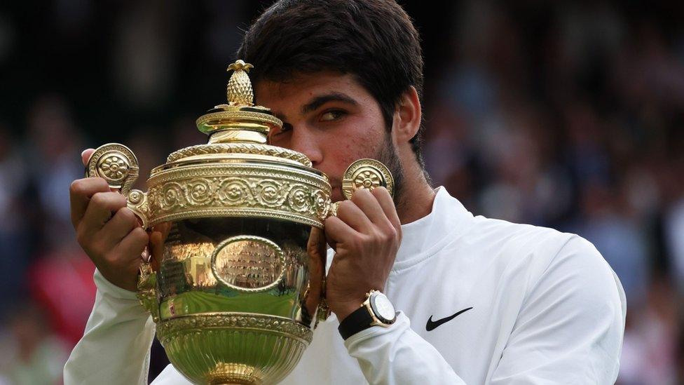 Carlos Alcaraz kisses his trophy after winning the men's singles title at Wimbledon