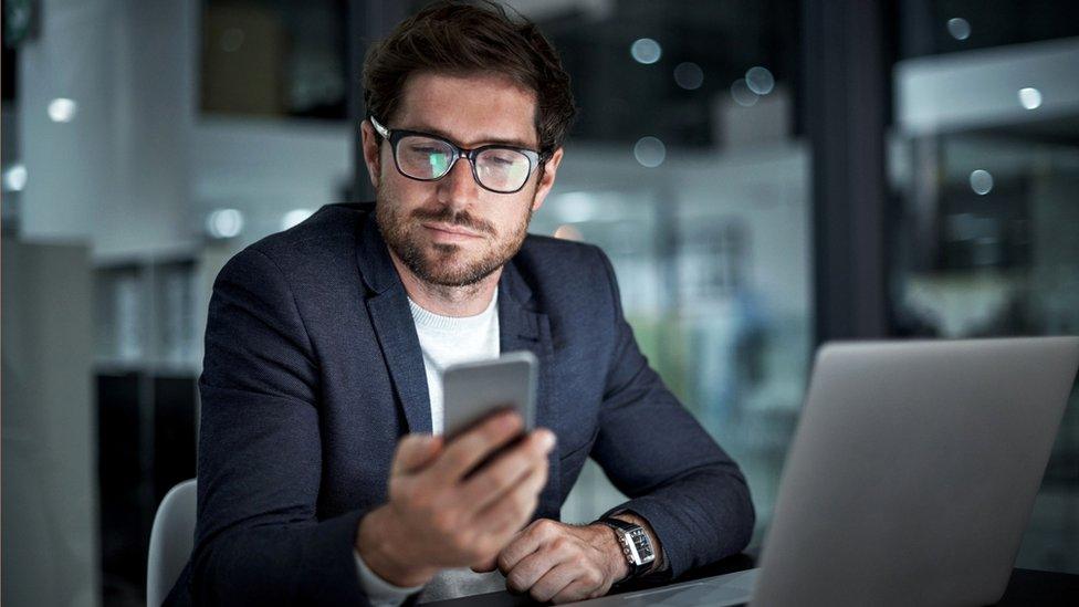 Man checking phone and laptop