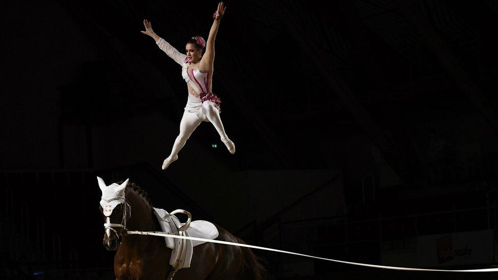 A woman jumps from her horse.