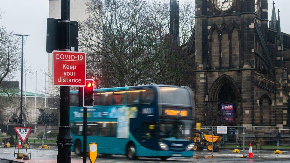 Newcastle civic centre with a bus in front of it and Covid sign