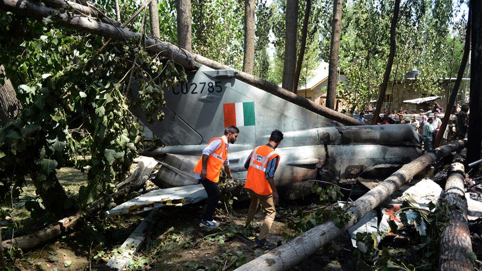 Disaster response personnel walk next to the wreckage of an Indian Air Force MiG-21 Bison aircraft that crashed in Soibugh on the outskirts of Srinagar on August 24, 2015.