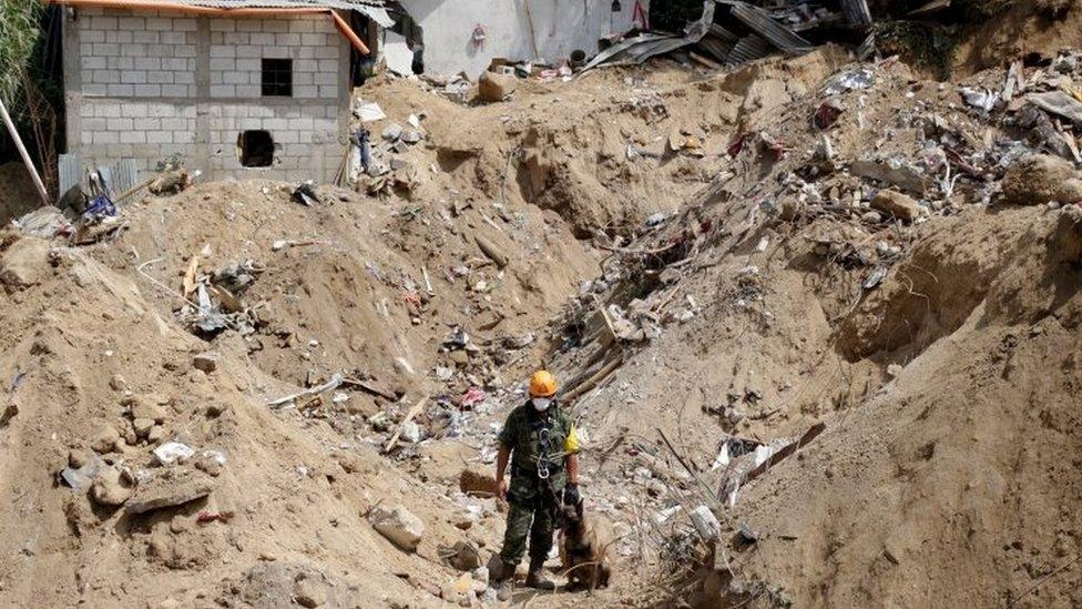 A Mexican Army rescue team member and his sniffer dog stand at an area affected by a mudslide in Santa Catarina Pinula on 4 October, 2015