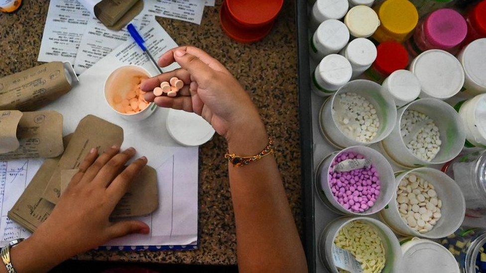 A Sri Lankan health workers is seen dispensing medicines into a container