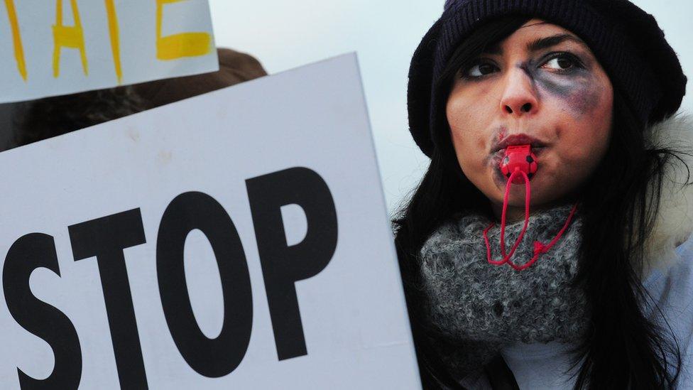 Romanian women, wearing make-up as part of a campaign against domestic violence, protest in front of the Romanian Parliament in Bucharest on 25 November 2011