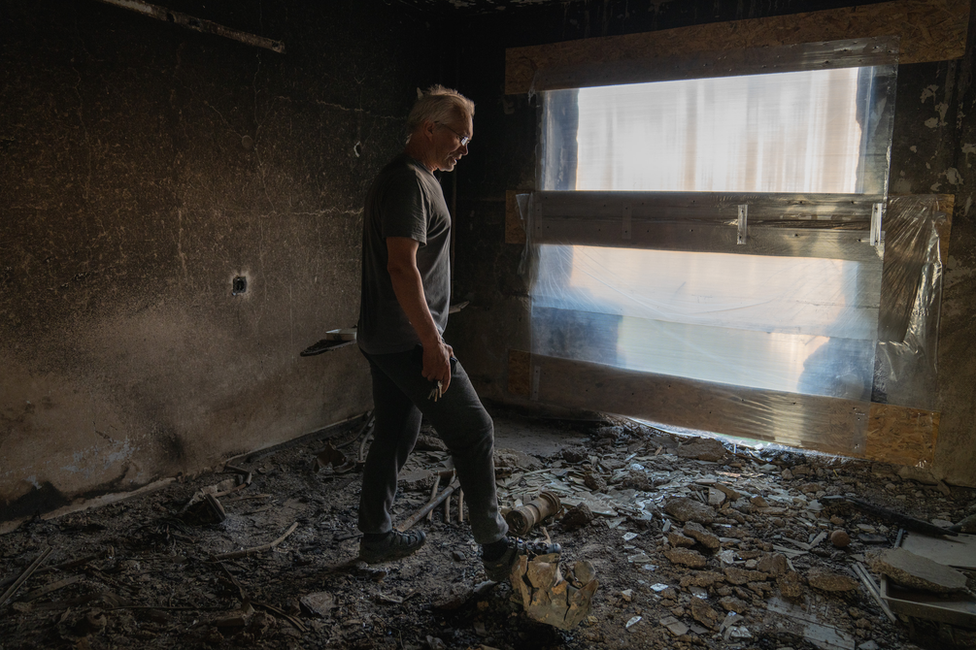 Boris Rustenko rests his foot on rocket shrapnel in his building. "Ukraine would have attacked Russia," he said. "Russia is just ahead"