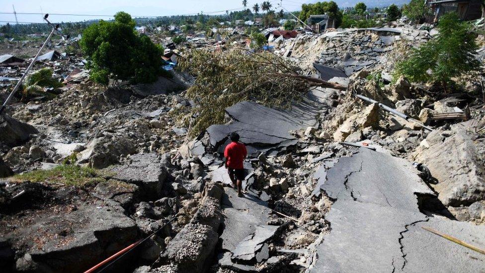 A man walks along a destroyed road in Palu, Indonesia's Central Sulawesi on October 2, 2018, after an earthquake and tsunami hit the area on September 28.