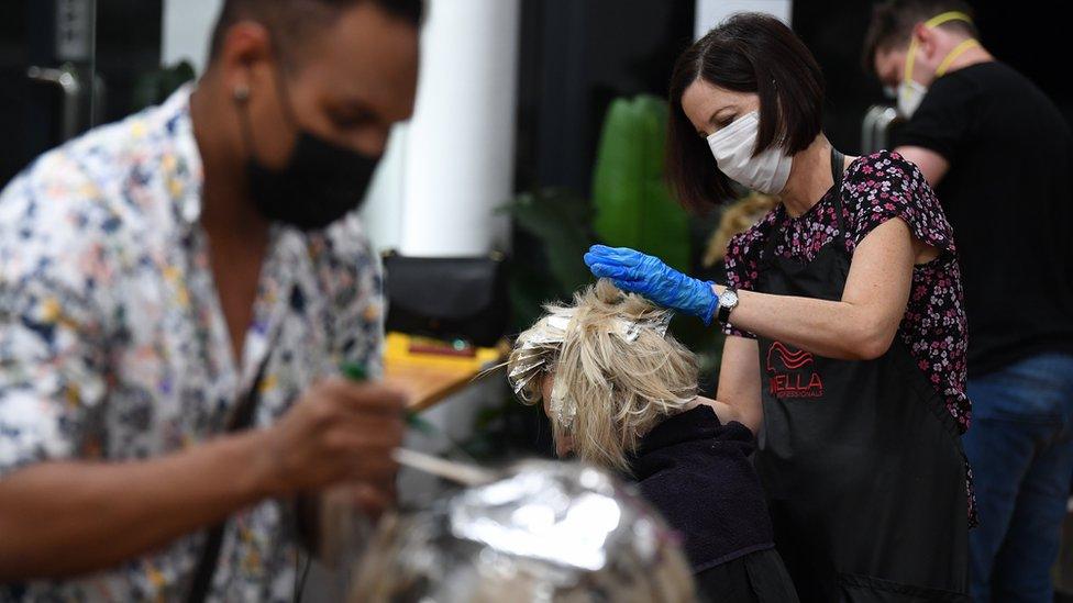 A hairdresser colors a customer"s hair in Brisbane, Australia, 25 March 2020