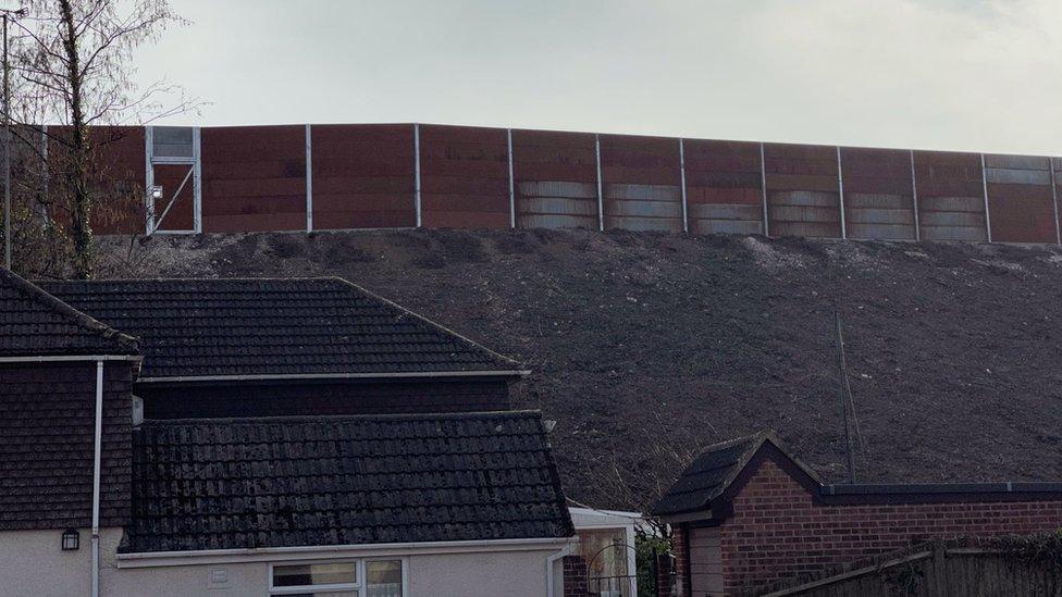 Steep bank and weathering steel wall behind a house