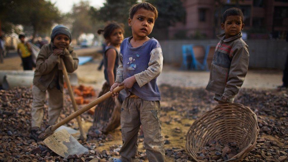 Indian children working at a construction project in front of the Jawaharlal Nehru Stadium