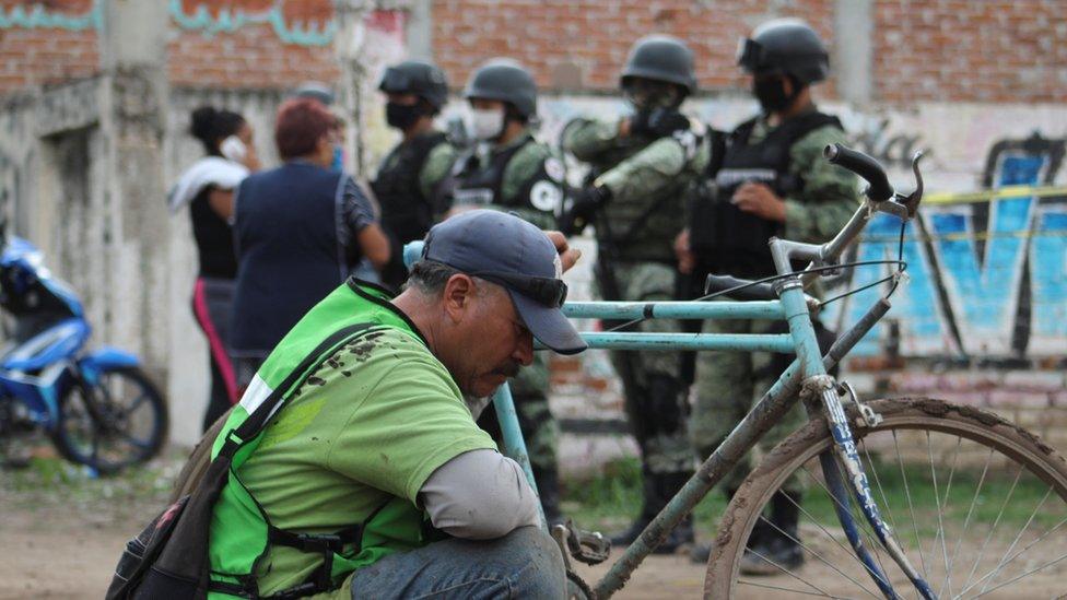 A man sits as soldiers keep watch outside a drug rehabilitation facility where assailants killed several people, according to Guanajuato state police, in Irapuato, Mexico July 1, 2020